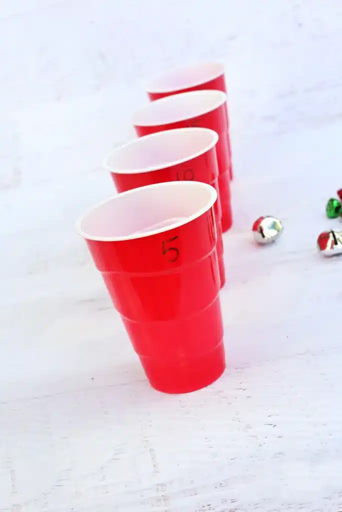 Jingle Bell Toss Reindeer Game - Cultivating Brilliant Minds red cups with numbers written on them and multicolored jingle bells