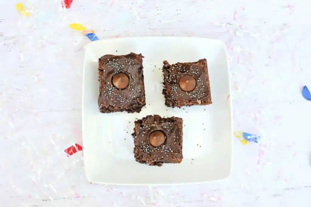 Midnight Kiss Brownies - Cultivating Brilliant Minds brownies with chocolate frosting, gold sprinkles, a hershey kiss in the middle