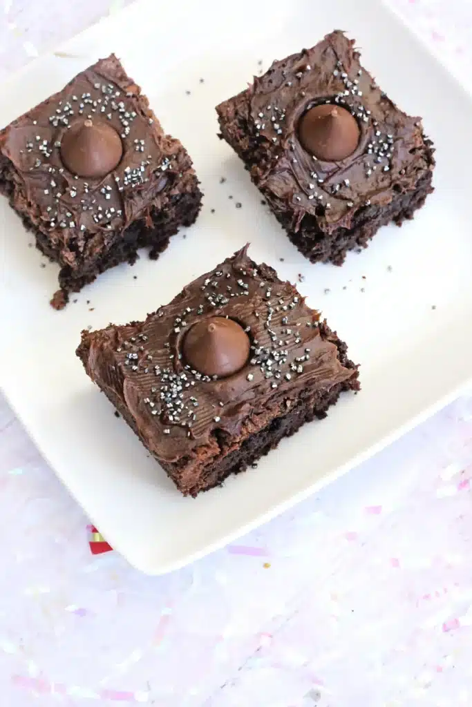 Midnight Kiss Brownies - Cultivating Brilliant Minds brownies with chocolate frosting, gold sprinkles, a hershey kiss in the middle