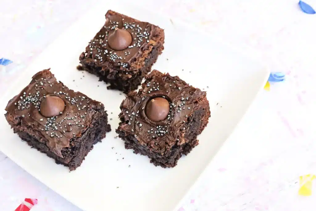 Midnight Kiss Brownies - Cultivating Brilliant Minds brownies with chocolate frosting, gold sprinkles, a hershey kiss in the middle