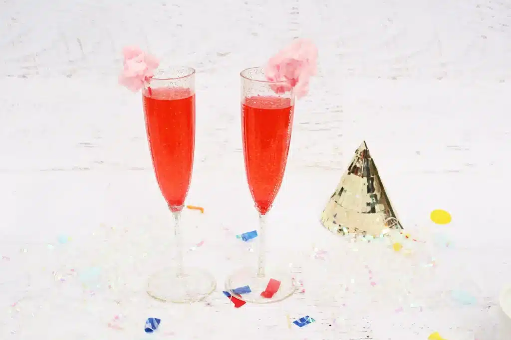 New Years Cotton Candy Drink  Cultivating Brilliant Minds a red new year's eve drink in a champagne glass with cotton candy on the top