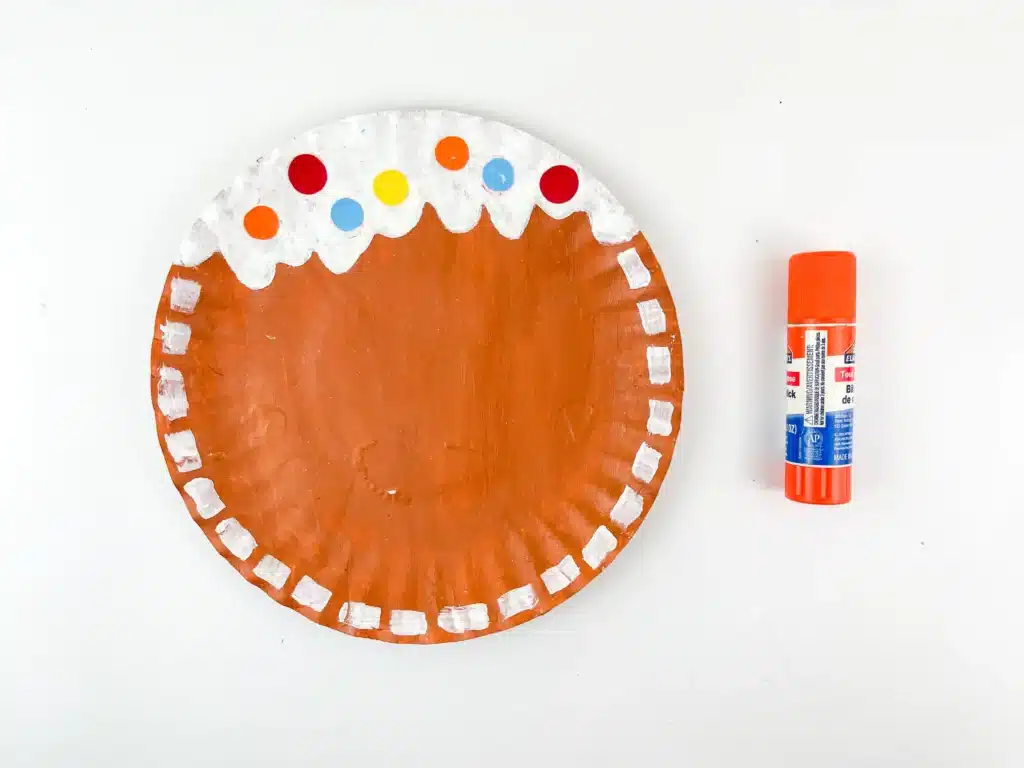 Gingerbread Paper Plate Craft - Cultivating Brilliant Minds a paper plate painted brown with white painted dots are the endge and scalloped at the top to look like icing with colored paper to look like gumdrops