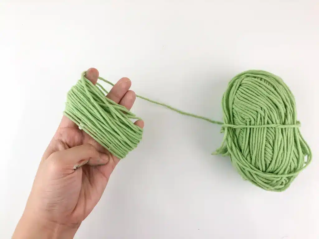 Yarn Ornament For Christmas - Cultivating Brilliant Minds green yarn wrapped around fingers