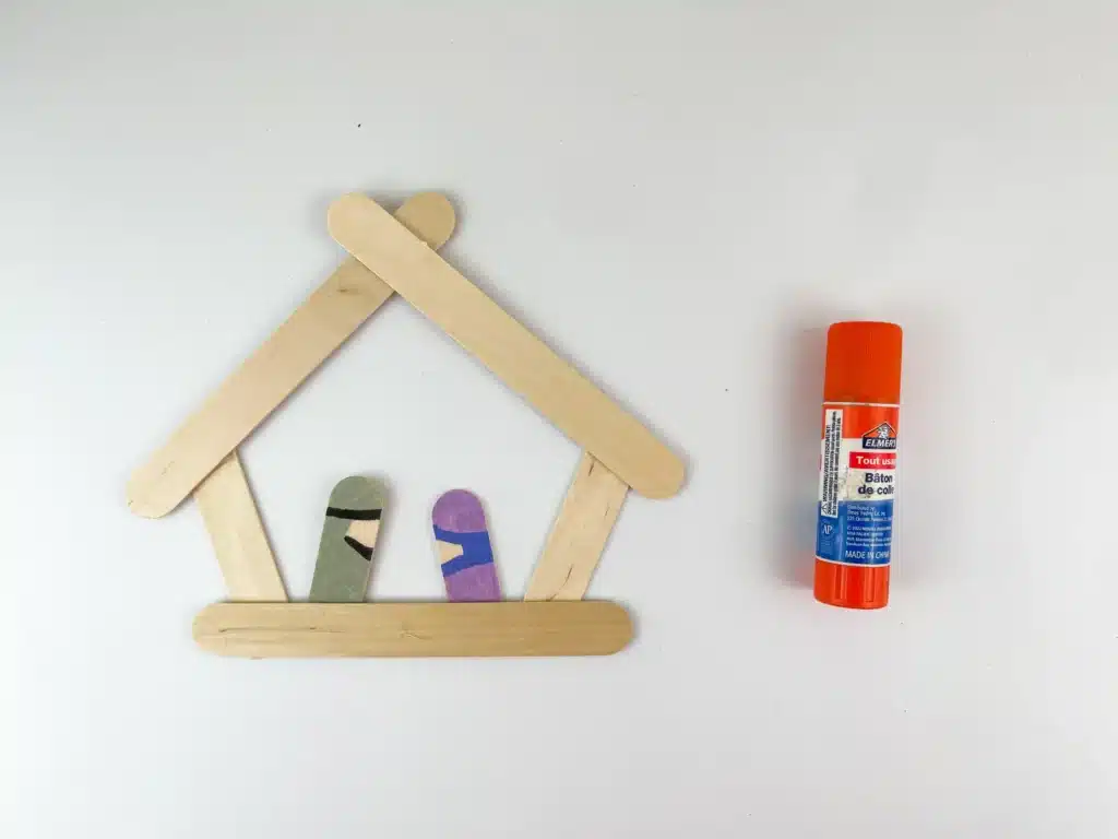 Nativity Popsicle Stick Craft - Cultivating Brilliant Minds popsicle sticks glued together to look like a manger with popsicle sticks colored to look like mary and joseph
