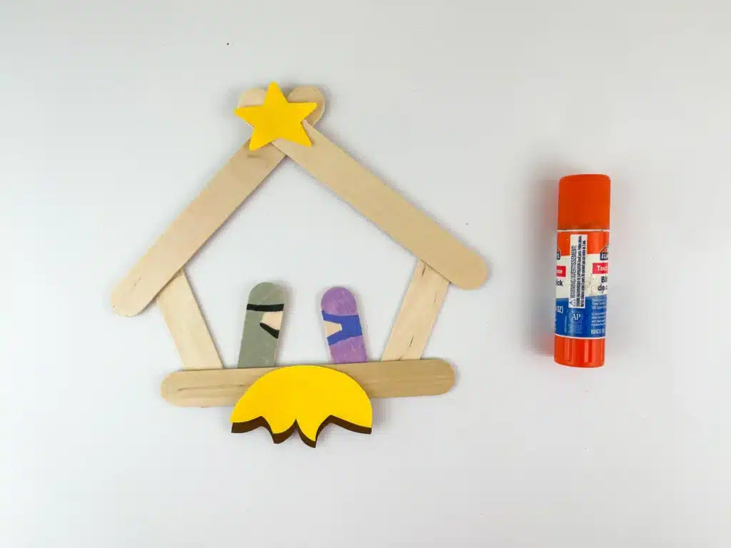 Nativity Popsicle Stick Craft - Cultivating Brilliant Minds popsicle sticks glued together to look like a manger with popsicle sticks colored to look like mary and joseph