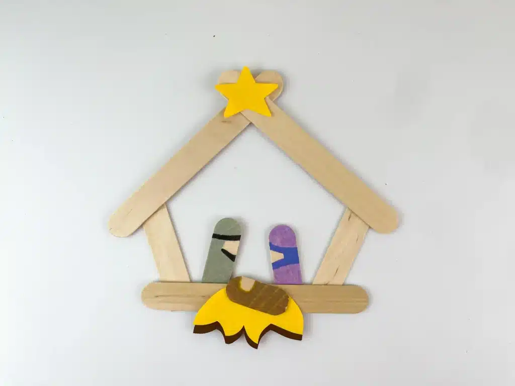 Nativity Popsicle Stick Craft - Cultivating Brilliant Minds popsicle sticks glued together to look like a manger with popsicle sticks colroed to look like mary, joseph, and jesus