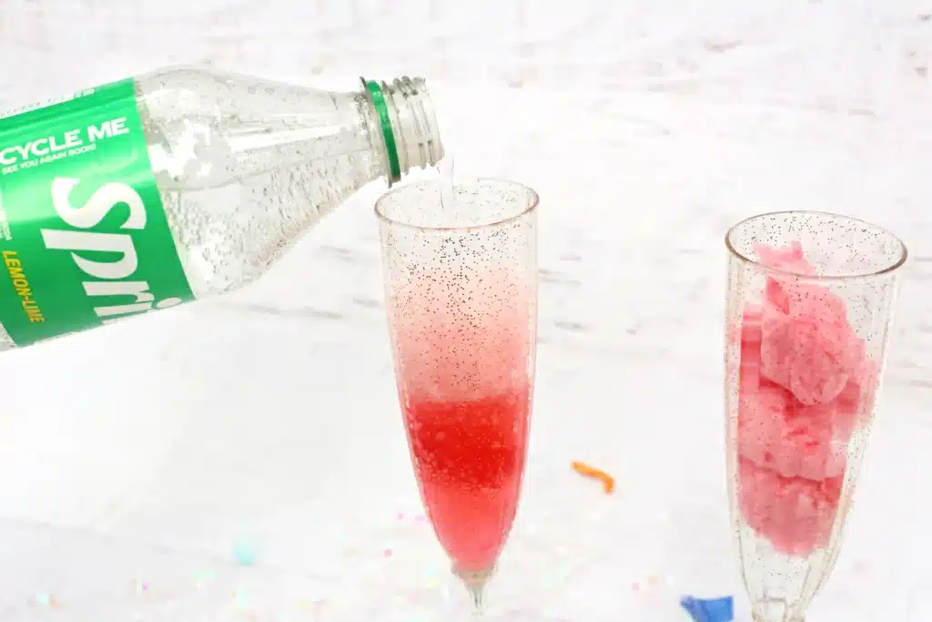 New Years Cotton Candy Drink  Cultivating Brilliant Minds pouring sprite into a glass with cotton candy in it