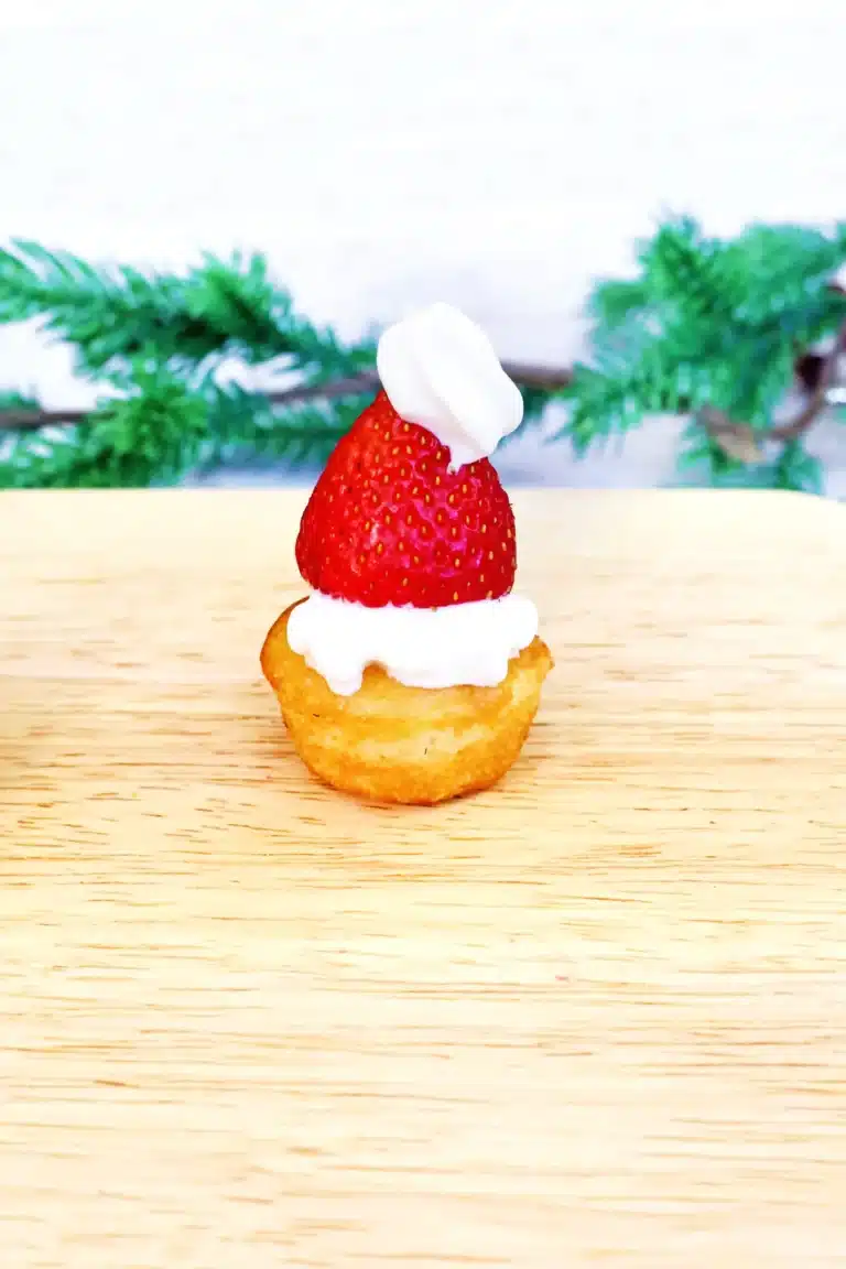 muffins with whipped cream and a strawberry to look like a santa hat