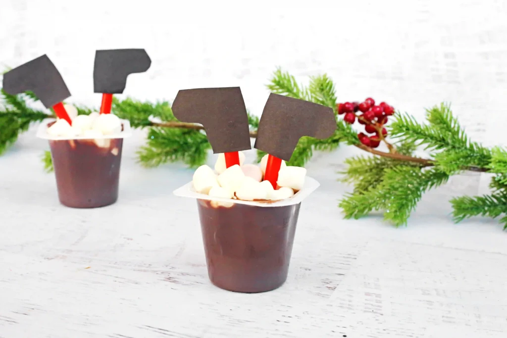Santa in the Chimney Pudding Snack - Cultivating Brilliant Minds A pudding cup decorated to look like santa is in the chimney with his legs sticking out