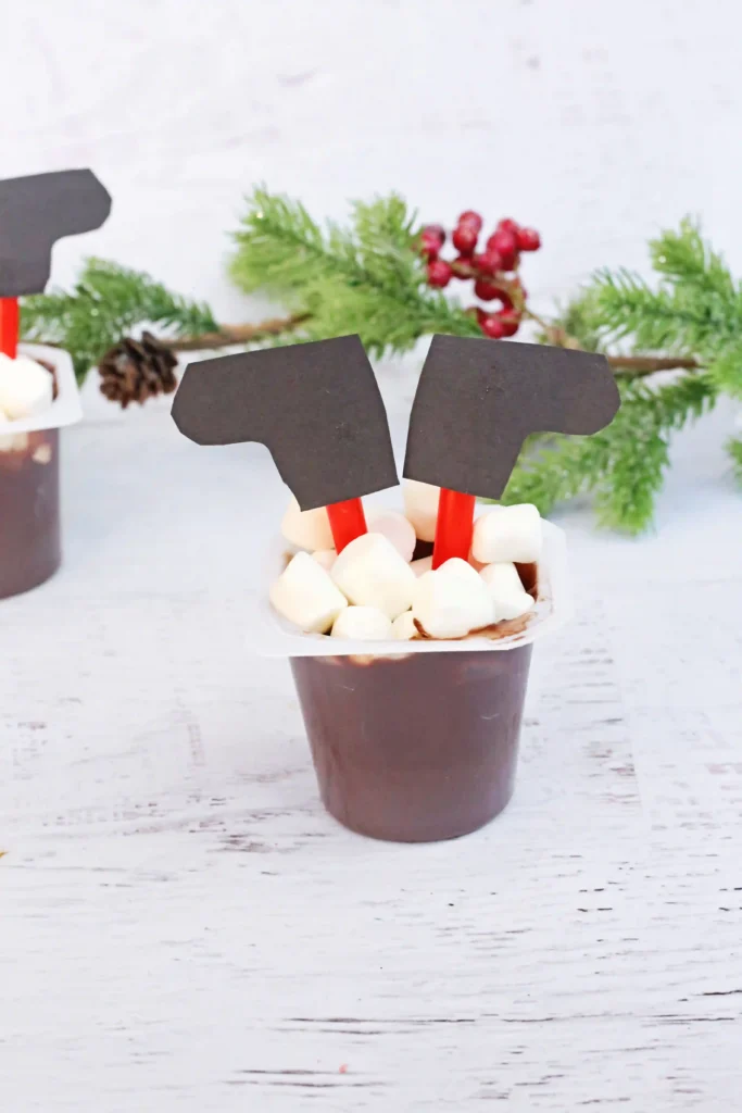 Santa in the Chimney Pudding Snack - Cultivating Brilliant Minds A pudding cup decorated to look like santa is in the chimney with his legs sticking out