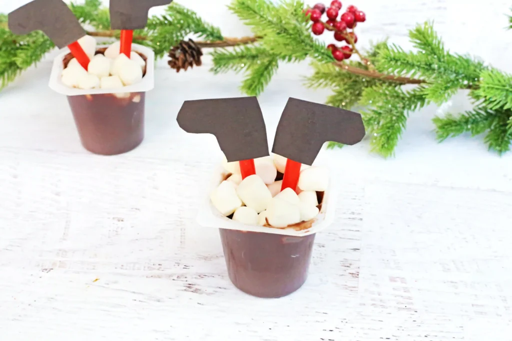 Santa in the Chimney Pudding Snack - Cultivating Brilliant Minds A pudding cup decorated to look like santa is in the chimney with his legs sticking out