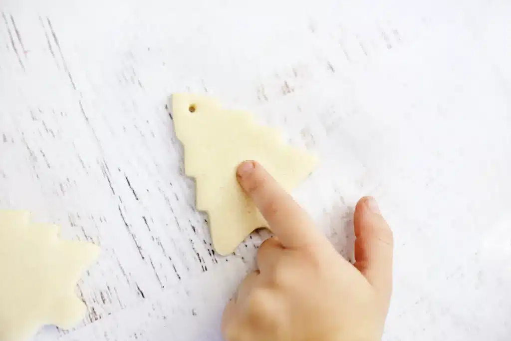 Fingerprint Salt Dough Christmas Tree Ornament - Cultivating Brilliant Minds a kid pressing fingerprints into the salt dough christmas tree