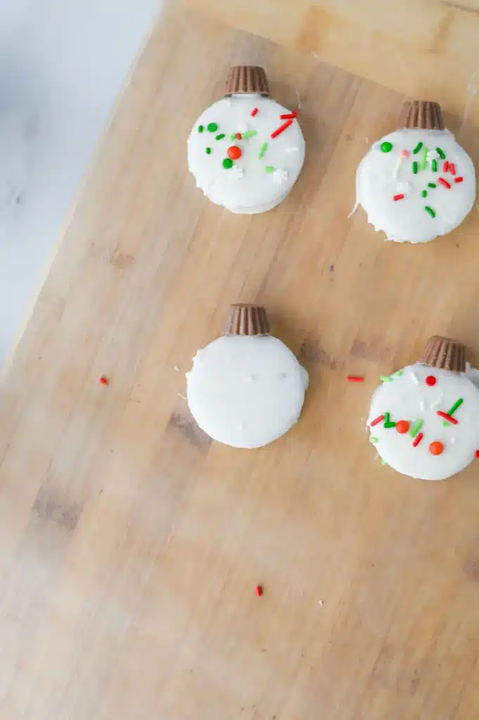 Oreo Ornament Cookies - Cultivating Brilliant Minds adding sprinkles and mini reeses to the oreo