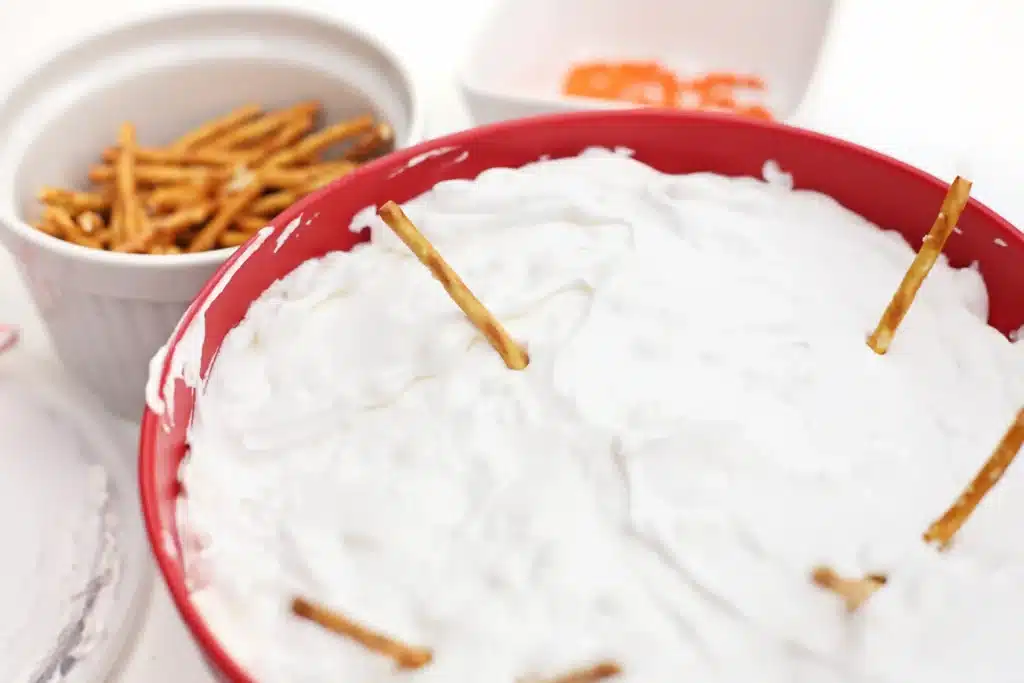 Melted Snowman Cheesecake Dip - Cultivating Brilliant Minds cream cheese, powdered sugar and whipped topping in a bowl with pretzel sticks