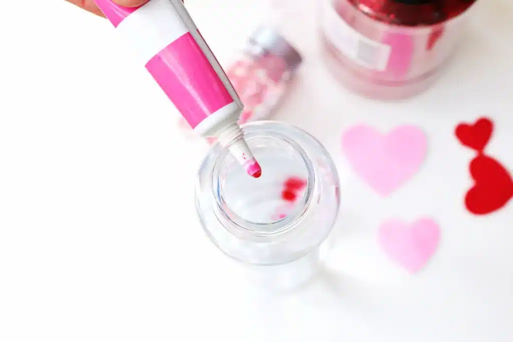 Love Potion Valentine Sensory Bottle - Cultivating Brilliant Minds pink food coloring being added to a bottle of water