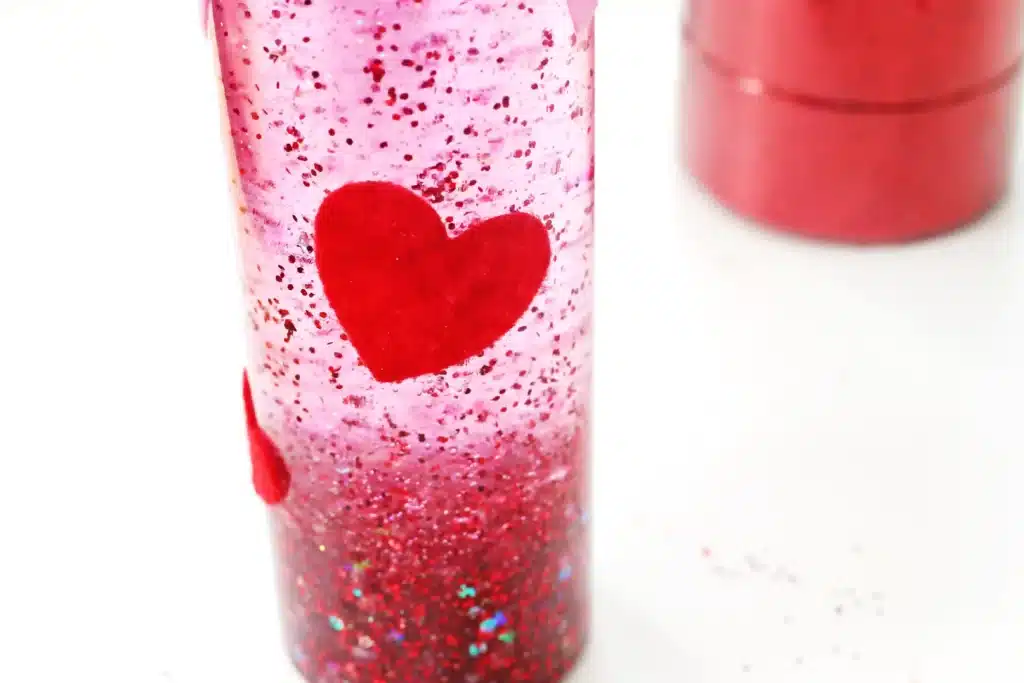 Love Potion Valentine Sensory Bottle - Cultivating Brilliant Minds a valentine's sensory bottle with red and pink felt hearts glued onto the outside