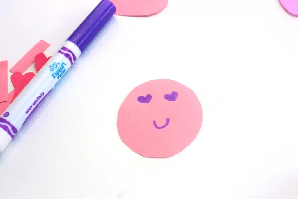 Heart Caterpillar Craft - Cultivating Brilliant Minds pink construction paper cut into a circle with a face drawn on in purple marker