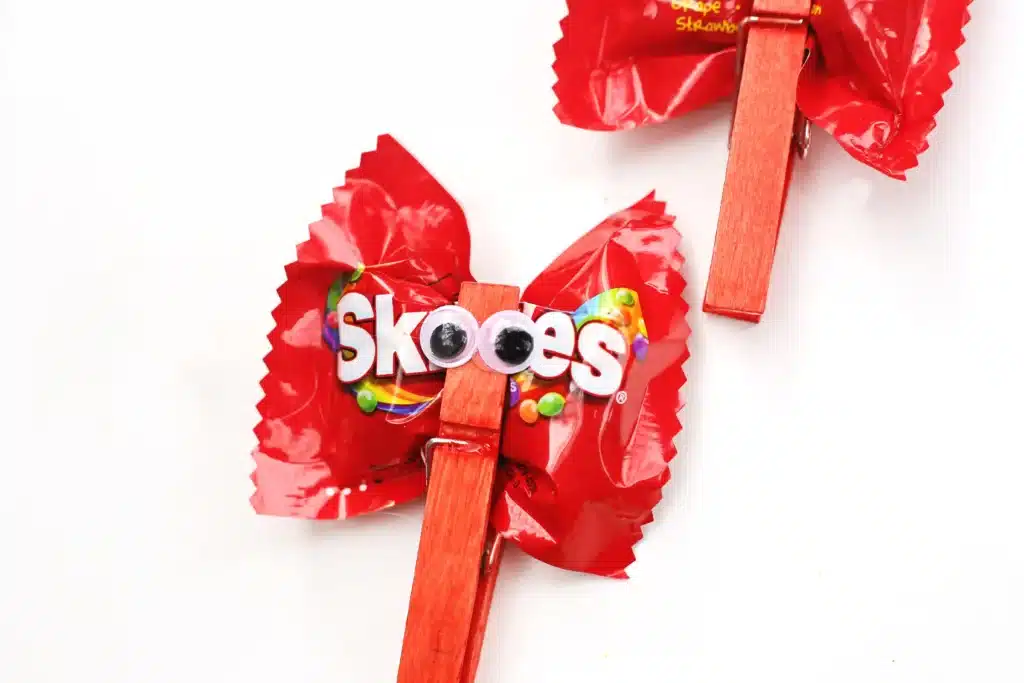 Valentine Candy Love Bugs - Cultivating Brilliant Minds a clothespin with googly eyes attached to a bag of skittles