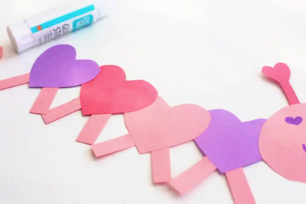 Heart Caterpillar Craft - Cultivating Brilliant Minds pink, red, and purple hears with pink construction paper rectangles attached to the bottom