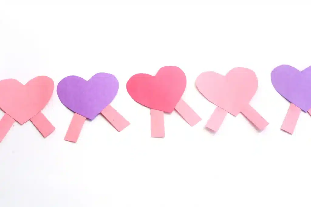 Heart Caterpillar Craft - Cultivating Brilliant Minds pink, red, and purple hears with pink construction paper rectangles attached to the bottom