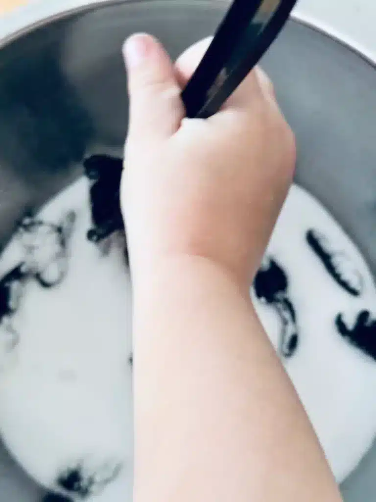 New Year's Eve Sensory Bin - Cultivating Brilliant Minds a kid mixing the salt and black paint