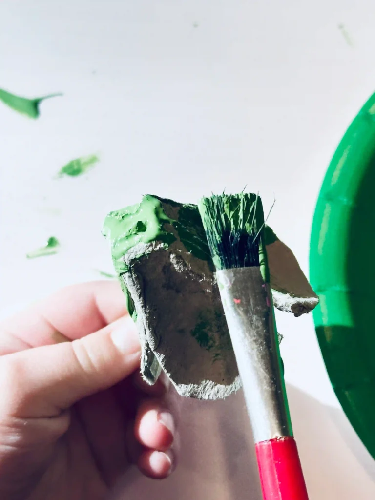 Egg Carton Sensory Bin - Cultivating Brilliant Minds painting the egg carton pieces green