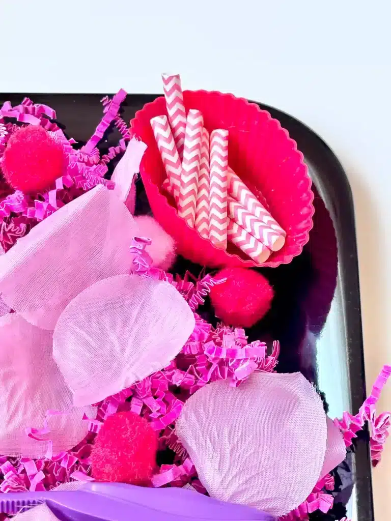 Valentine's Day Sensory Bin - Cultivating Brilliant Minds a valentine's day sensory bin with crinkle paper. rose petals, pom poms, and straws