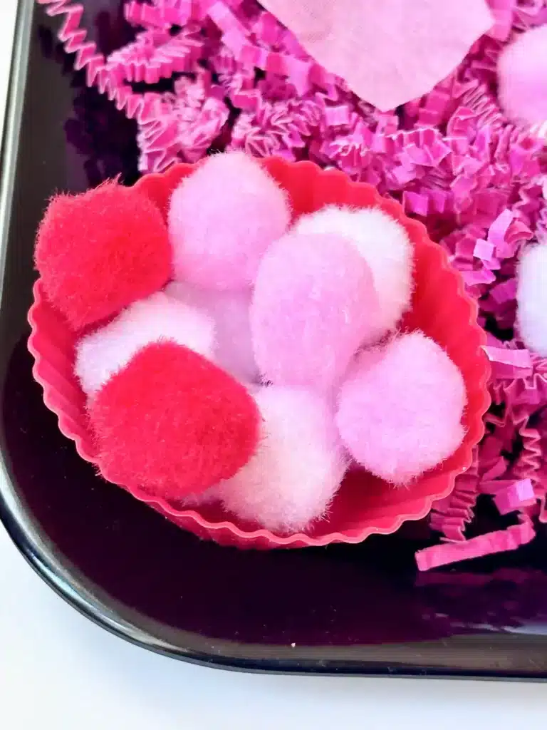 Valentine's Day Sensory Bin - Cultivating Brilliant Minds a valentine's day sensory bin with crinkle paper. rose petals, pom poms, and straws