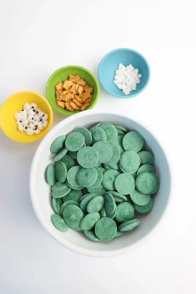 Mardi Gras Nutter Butter Alligators - Cultivating Brilliant Minds green candy melts, candy eyes, nutter butters, crown sprinkles, and white heart sprinkles