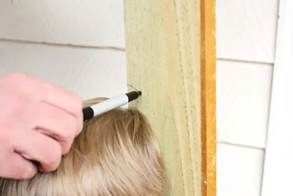 Wooden Gingerbread Keepsake Craft - Cultivating Brilliant Minds measuring and marking a child's height on a wooden board