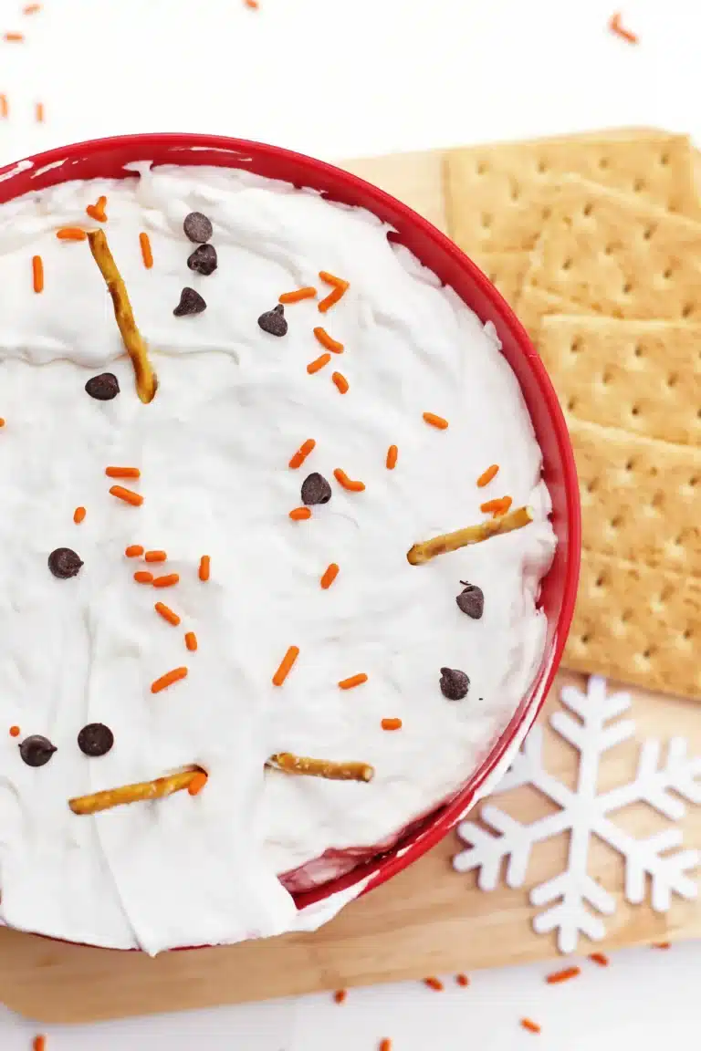 melted snowman cheesecake dip with mini pretzel sticks, crackers, and chocolate chips