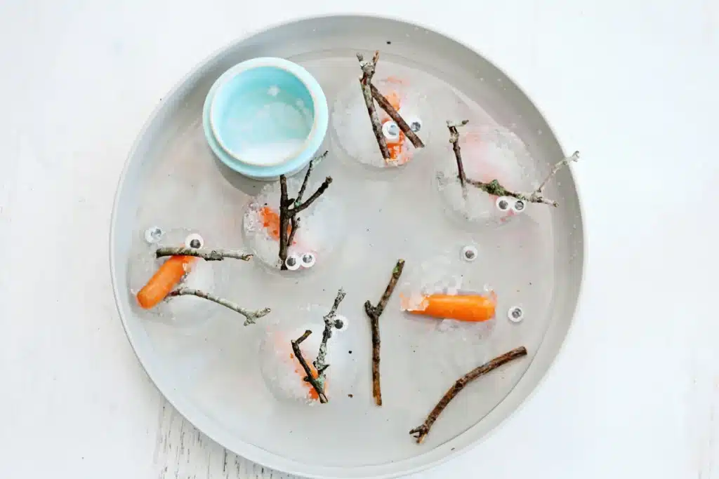 Melting Snowman Sensory Activity - Cultivating Brilliant Minds snowman pieces frozen in ice on a plate
