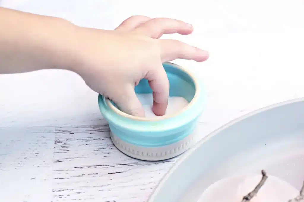 Melting Snowman Sensory Activity - Cultivating Brilliant Minds a child grabbing a pinch of salt