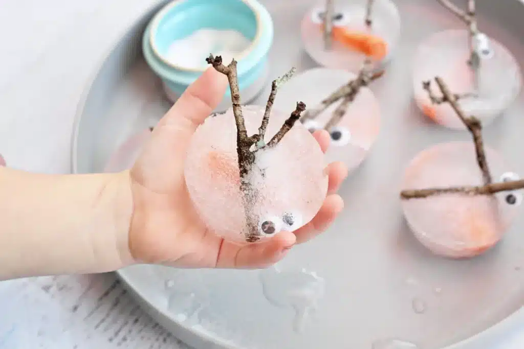 Melting Snowman Sensory Activity - Cultivating Brilliant Minds a kid holding snowman pieces frozen in ice