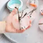 Melting Snowman Sensory Activity - Cultivating Brilliant Minds a kid holding snowman pieces frozen in ice