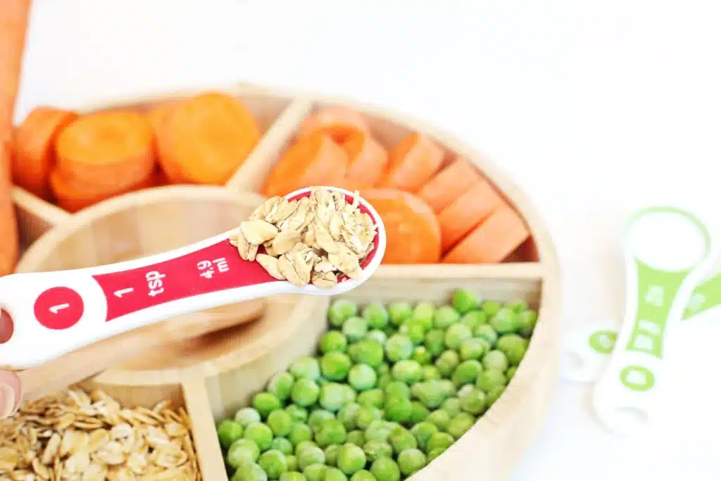 Reindeer Bait Sensory Bin - Cultivating Brilliant Minds a reindeer sensory bin filled with rolled oats, sliced carrots, and peas