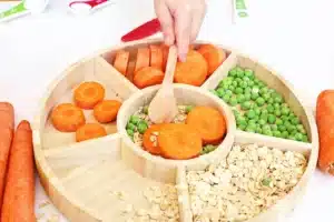 a reindeer sensory bin filled with rolled oats, sliced carrots, and peas