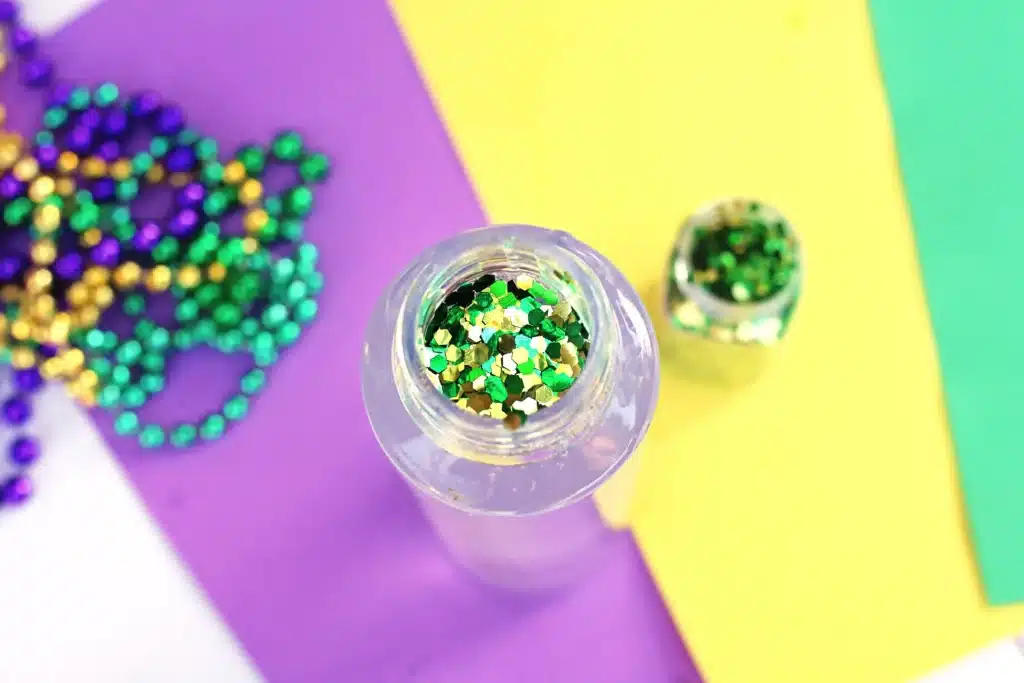 Mardi Gras Sensory Bottle - Cultivating Brilliant Minds glitter in a water bottle with water and glue