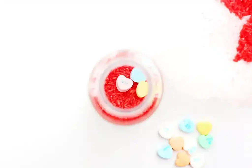 Valentine's Day Candy Heart Sensory Bottle - Cultivating Brilliant Minds red rice in an empty water bottle with candy hearts