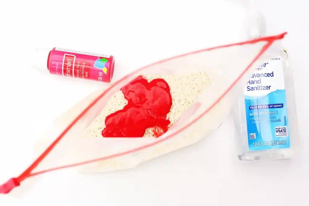 Valentine's Day Candy Heart Sensory Bottle - Cultivating Brilliant Minds uncooked rice in a bag with hand sanitizer and red food dye