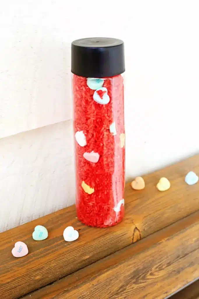 Valentine's Day Candy Heart Sensory Bottle - Cultivating Brilliant Minds a candy heart sensory bottle that uses red rice and candy hearts
