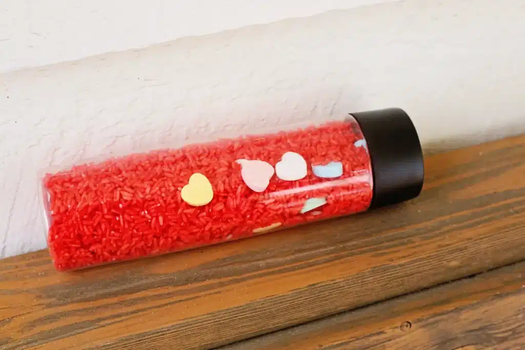 Valentine's Day Candy Heart Sensory Bottle - Cultivating Brilliant Minds a candy heart sensory bottle that uses red rice and candy hearts