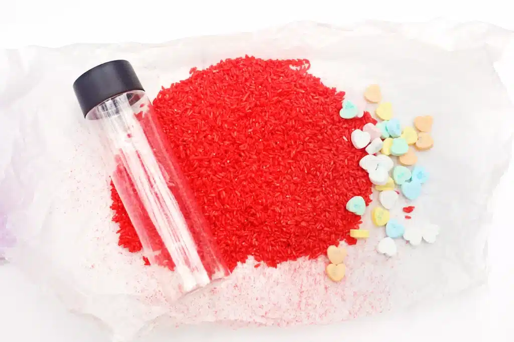Valentine's Day Candy Heart Sensory Bottle - Cultivating Brilliant Minds an empty water bottle, rice dyed red, and candy hearts