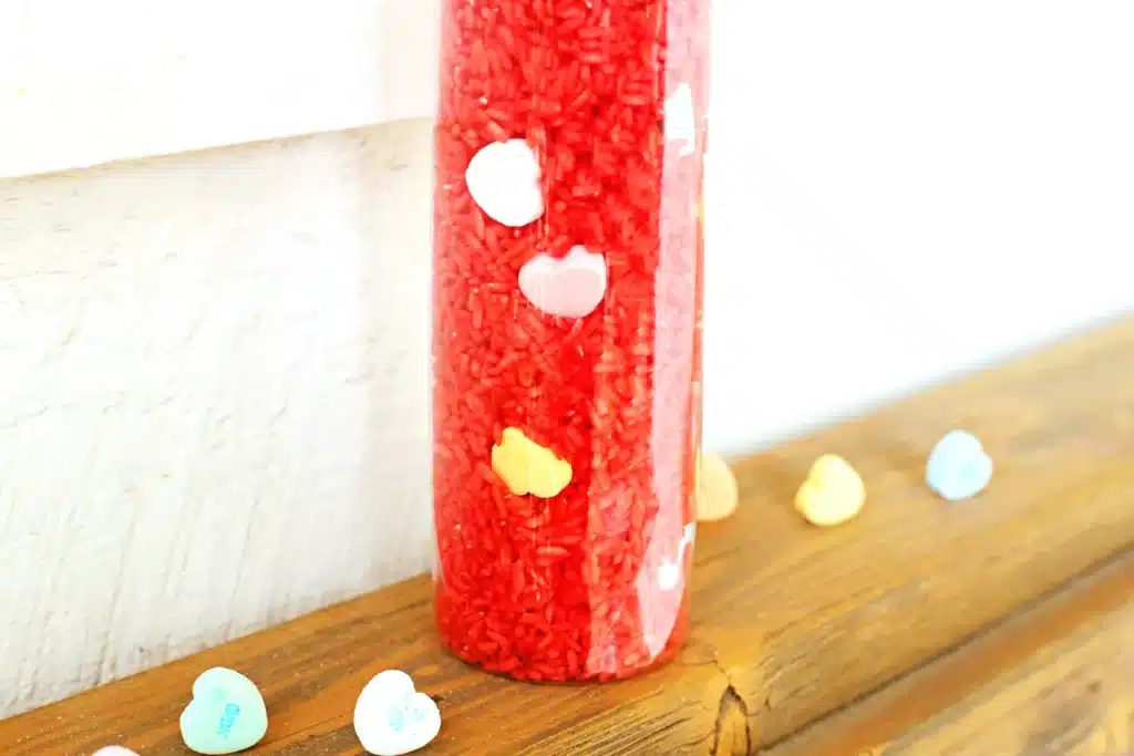 Valentine's Day Candy Heart Sensory Bottle - Cultivating Brilliant Minds a candy heart sensory bottle that uses red rice and candy hearts