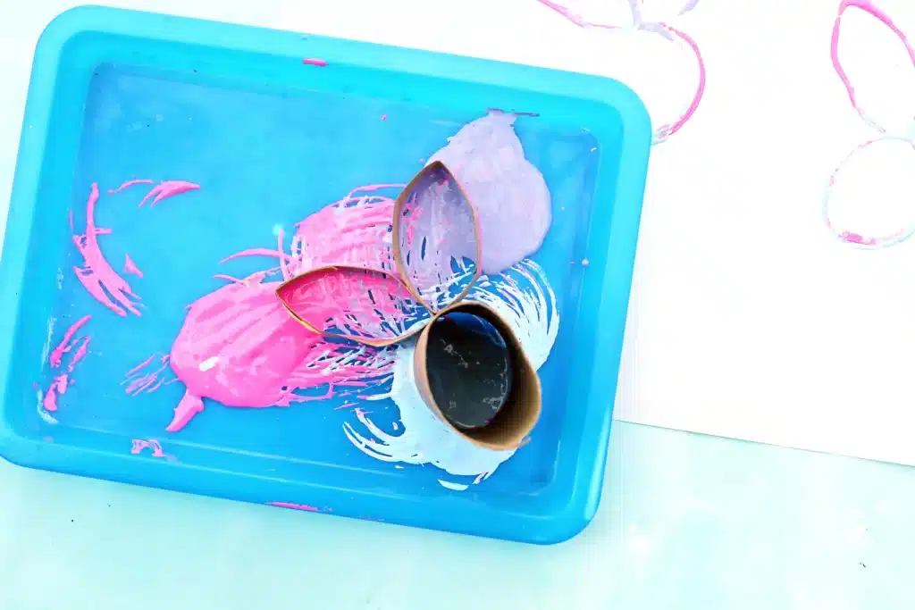 Bunny Stamp Art with Toilet Paper Rolls - Cultivating Brilliant Minds a toilet paper roll with two small sections cut off, shaped into bunny ears, and glued onto the toilet paper roll dipped in 3 colors of paint