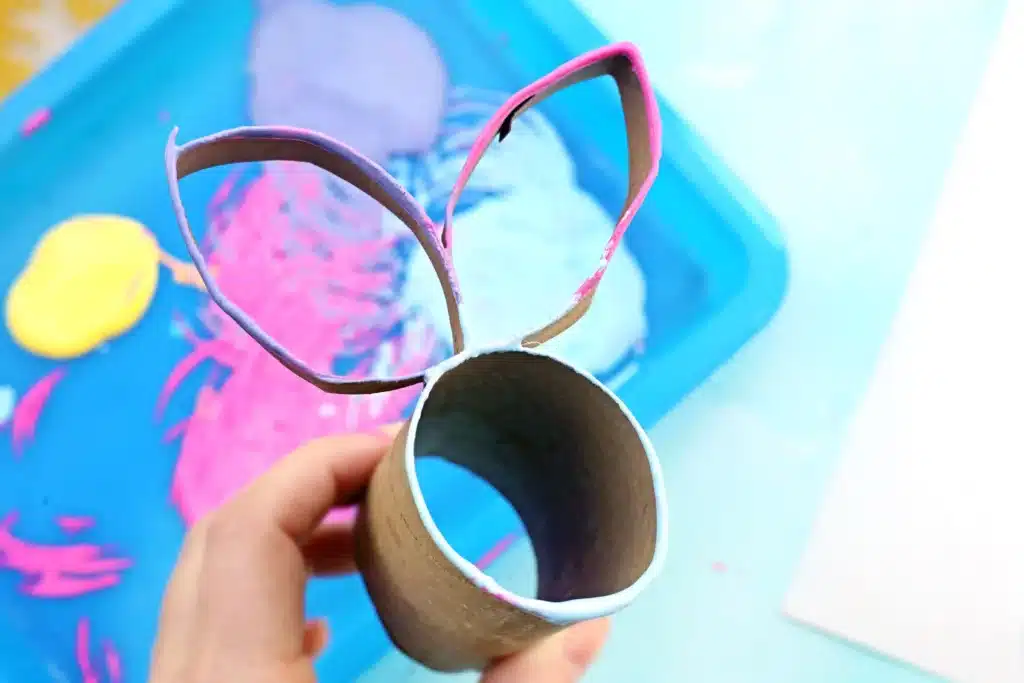 Bunny Stamp Art with Toilet Paper Rolls - Cultivating Brilliant Minds a toilet paper roll with two small sections cut off, shaped into bunny ears, and glued onto the toilet paper roll with paint on it