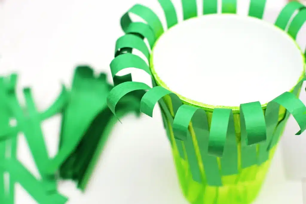 Groundhog Day Craft For Kids - Cultivating Brilliant Minds a foam cup painted green with strips of green construction paper glued on and curled to look like grass