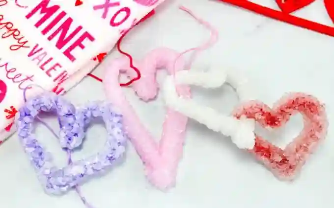 Heart-Themed Crafts For Kids This Valentine's Day - Cultivating Brilliant Minds pipe cleaners shaped like hearts with salt "crystals" on them.