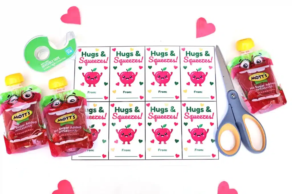 Printable Valentines: Hugs and squeezes - Cultivating Brilliant Minds printable valentines that read "hugs and squeezes" with an apple on it, a squeezable applesauce, tape, and scissors.