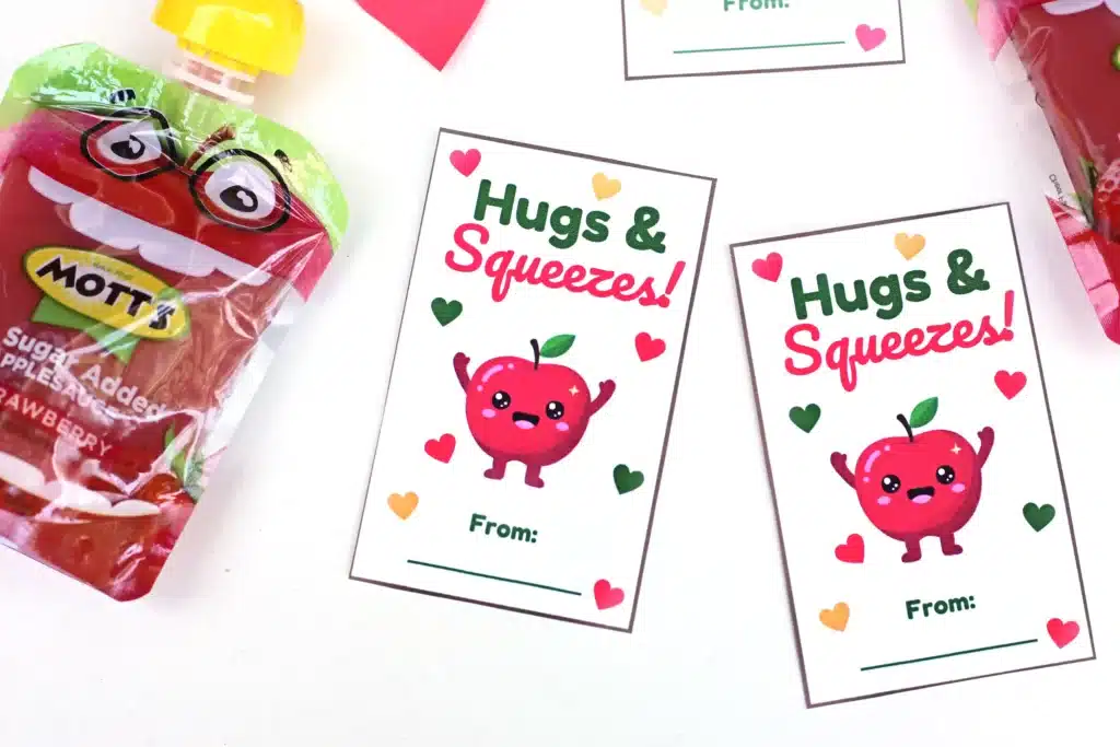 Printable Valentines: Hugs and squeezes - Cultivating Brilliant Minds printable non-candy valentines using a squeezable applesauce and a valentine that reads "hugs and kisses" and has an apple on it.